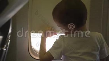 小男孩坐在座位上，打<strong>开飞机</strong>窗